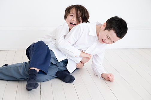 a professional photograph of two brothers having fun at a natural family photoshoot in a white studio in glasgow